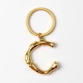 Macro detail of a golden metal letter C keychain with a polished shiny gold keyring - Letter C