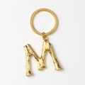 Detailed view of a shiny gold letter M keychain pendant with a polished metallic finish - M