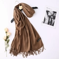 Detailed macro view of a brown cashmere scarf featuring fringe edges and a woven brand label - Mocha