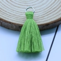 Grass green cotton tassel pendant with silver metal ring on a wooden background - Dried Grass Green