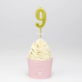 Matte golden number 9 birthday candle on a decorated cupcake against a grey background - Number 9