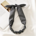 Diadema elástica de tela gris con nudo de orejas de conejo sobre fondo minimalista - gris oscuro
