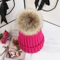 Detail view of pink knitted beanie with a large beige faux fur pompom for winter - Adult One Size 56-58cm / Rose Red