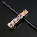 Detail of acetate marble pattern hair clip with golden metal grip on reflective surface - Colorful Marble
