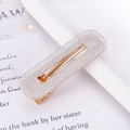 Detail of silver glitter acetate hair clip with golden metal base on a magazine page - Glitter Silver Square
