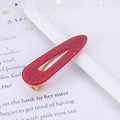 Detalle de pinza para el pelo con purpurina roja y base de metal dorado sobre fondo de revista - Purpurina Rojo Gota de Agua