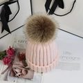 Rosa Strickmütze mit großem Kunstfell-Bommel auf dekorativem Geschenkhintergrund - Hellrosa