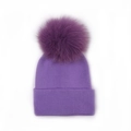 Detailed close-up of purple knit baby beanie featuring a large fluffy faux fur pompom - Violet