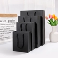 Matte black kraft gift bags with nylon handles in four various sizes on white background - 14.5x7x15cm / Black