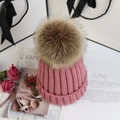 Detailansicht der rosa Strickmütze mit großem Kunstfell-Bommel und festlichem Geschenkdekor - Altrosa
