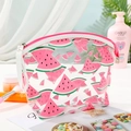 Close-up of a clear PVC watermelon pouch with pink zipper and white handle on a vanity - Pink