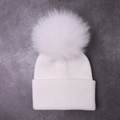 White ribbed knit baby beanie with a large fluffy pom-pom in a minimalist winter style - White
