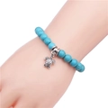 Turquoise beaded bracelet with antique silver turtle charm worn on a wrist - 8mm Bead / Green