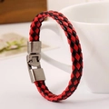 Pulsera de cuero trenzado en rojo y negro con cierre metálico junto a una taza blanca - Rojo+Negro
