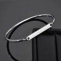 Polished silver metal cuff bracelet with rectangular plaque displayed on jewelry box - Steel