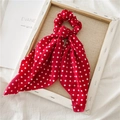 Detail van rode polka dot scrunchie met lang lint op een rustieke houten lijst - Rode Polka Dot