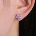 Elegant pink flower stud earrings with zirconia crystals worn on ear for a stylish look - Pink