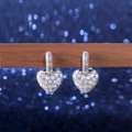 Detalle de pendientes de corazón plateados con pavé de circonitas en soporte de madera - Plata