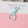 Detalle de cierre de mosquetón azul claro con anillos metálicos sobre fondo rosa limpio - Verde Menta