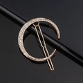 Barrette à cheveux dorée en forme de lune avec strass brillants sur fond noir - Lune Dorée