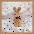 Close-up of soft plush rabbit keychain with brown bow on white knitted background - Coffee Rabbit