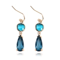 Detailed macro shot of dark blue teardrop crystal earring with golden copper trim - Blue