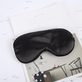 Close-up of black silk sleep mask with satin texture on white magazine background - Black