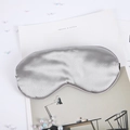 Detailed view of silver silk sleep mask with elastic strap on minimalist aesthetic magazine - Gray