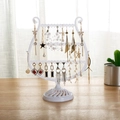 Creative harp-shaped white jewelry organizer rack displaying various earrings on a wooden table - White
