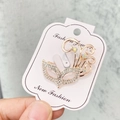 Élégante broche masque en or rose avec strass brillants sur une carte de présentation - A7-7