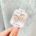 Broche nœud dorée avec perles blanches et strass sur carte de bijoux de mode - A7-11