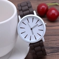 Slim silicone quartz watch with white dial and brown strap resting on wood surface - Brown