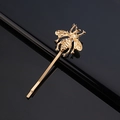 Detail einer goldenen Bienen-Haarklammer mit Flügelstruktur auf schwarzem Hintergrund - Metall Gravierter Stil / Gold Biene