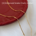 Macro-opname van een gouden slangenketting op een rood geschulpt porseleinen bord - Reliëf Slangenketting / 45 cm / Goud