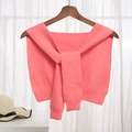 Knitted coral pink shawl wrap with tie detail shown on a wooden hanger - Watermelon red