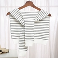 Knitted shawl wrap in white and black stripes with ribbed cuffs on a wooden hanger - Striped White