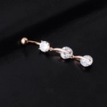 Close-up of rose gold belly ring featuring three sparkling round zircon stones on dark texture - Rose Gold