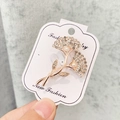 Broche tulipe dorée élégante avec strass blancs et perles sur une carte de bijoux - A7-1