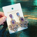 Elegant purple crystal teardrop earrings with gold plating shown held by hand - Long Waterdrop Gemstone Style / Purple