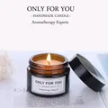Scented soy wax candle in amber glass jar with lid, burning on a vintage magazine page - No Flowers
