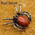 Silver-tone spider brooch with an oval red jasper stone set on a textured woven background - Red Jasper