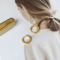 Dettaglio di orecchini a cerchio placcati oro 18K su una rivista alla moda e chic - Oro