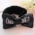 Detail shot of black plush headband featuring faux leather OMG bow on pink background - Black