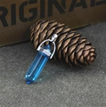 Blue hexagonal crystal pendant with silver clasp resting on a rustic wooden box - Sea Blue Crystal