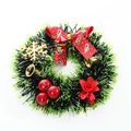 Green tinsel Christmas wreath with red bow, golden bells, and holly berry accents - Printed Bow Snowflake Rose Style