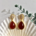 Detailed close-up of red teardrop agate earrings in gold setting with pavé zircon accents - Gold+Red