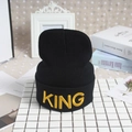 Bonnet noir en tricot avec broderie King jaune sur surface de tuiles et de livres - Style KING / Noir Jaune KING