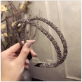 Primer plano de dos diademas de color gris oscuro con cristales brillantes sujetas a mano - Gris