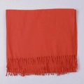 Thick orange red cashmere-like scarf with fringe tassels on a textured surface - Rust red