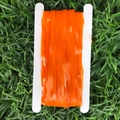 Detalle de cortina de flecos naranja mate en carrete blanco con fondo de césped verde - 2 Metros de Flecos Naranjas / Cinta